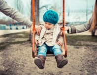 Mother and father in a custody dispute, while their child sits on a swing between them 